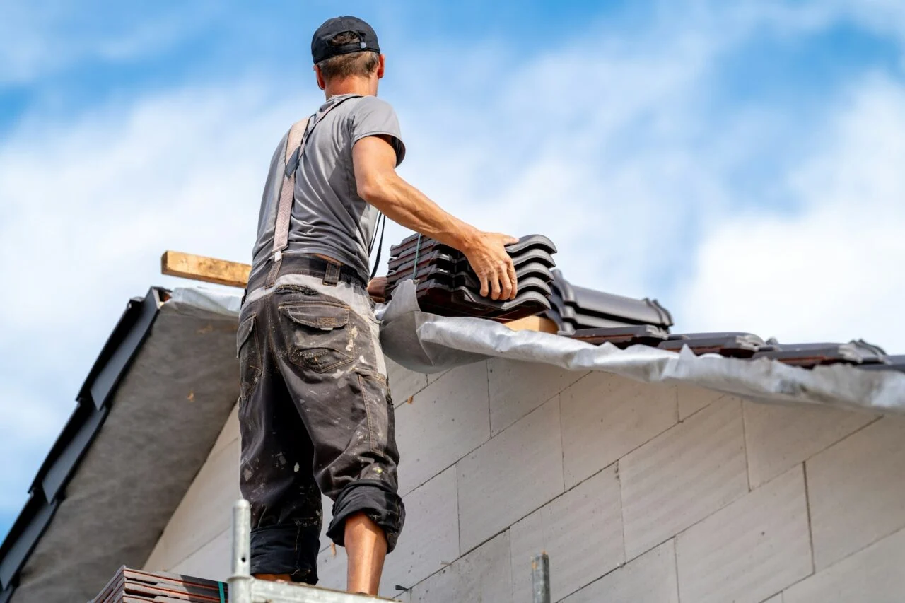 Roofer on the roof of a family house building a roof covering from ceramic tiles